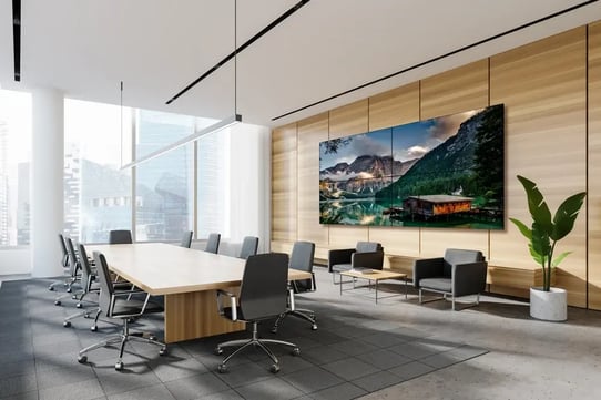 Modern conference room with a large wall display showing a mountain landscape above a lounge seating area.