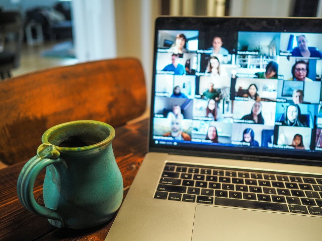 A laptop screen displaying a group of people in a virtual meeting